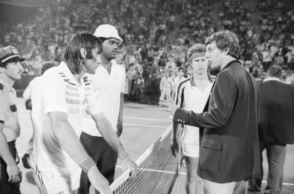 Nastase discute con il direttore di torneo, mentre McEnroe osserva